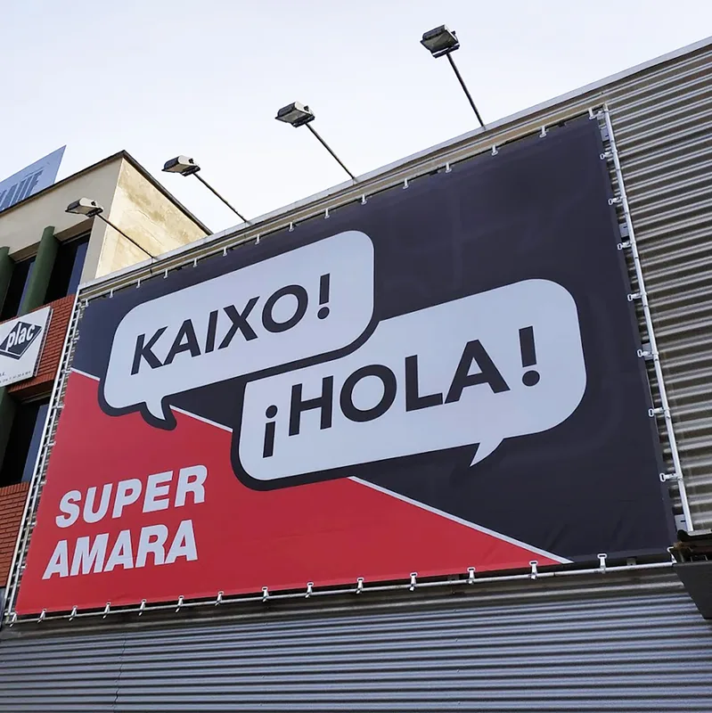 Pancarta de gran formato instalada en una fachada con el saludo de una campaña promocional