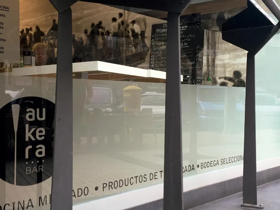 Paneles de cristal de la terraza de un bar rotulados en vinilo con el logotipo y los reclamos del local